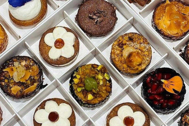 A box of small French tarts, fruit, chocolate and caramel, seen from above