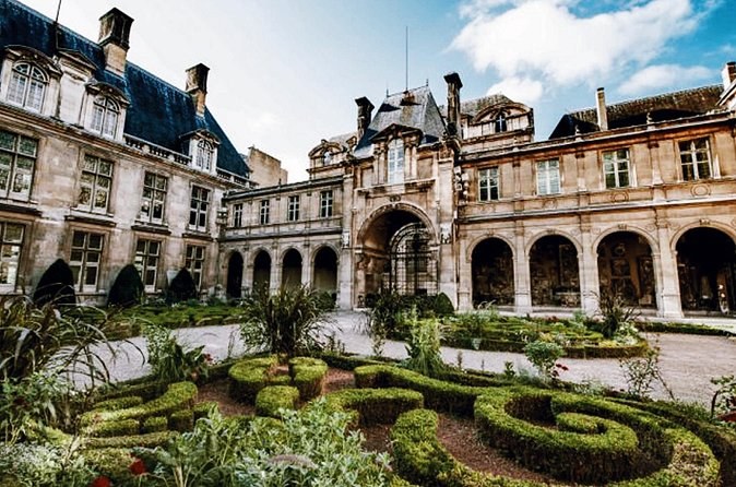 A box-hedge parterre in the courtyard of a Marais townhouse, arcades on two sides