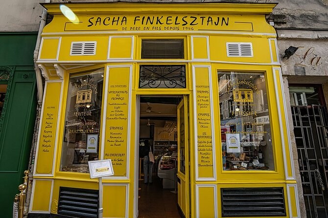 The bright yellow front of a Jewish bakery and delicatessen in the Marais, its windows lettered with what it sells
